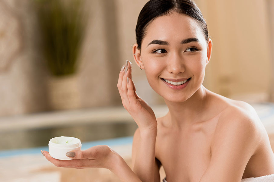 Attractive asian woman applying cosmetic cream